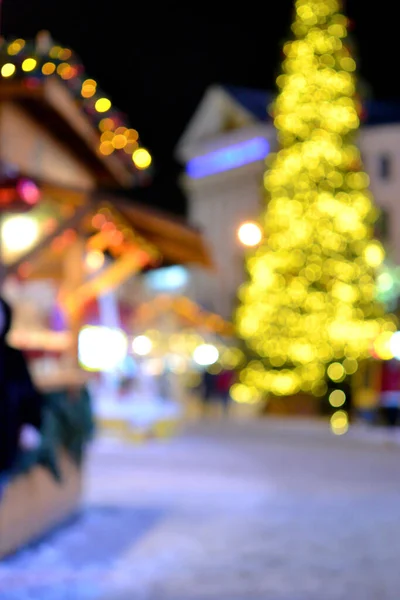 흐릿하다 크리스마스 나무는 노란색으로 장식되어 지붕에 등불로 거리를 사람들의 실루엣으로 — 스톡 사진