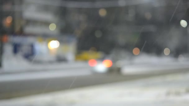 背景がぼやけている 冬の夜に雪の中 街の道路に沿って車を運転 ブラリーボケスポット 街路灯 ランタン 明るいヘッドライトの光 冬の風景 テクスチャの背景 — ストック動画