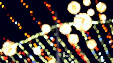 Arka plan bulanık. Güzel, parlak ve parıldayan yeni yıl süsleri ve Noel çelenkleri ve parıldayan toplar siyah gecelerde açık havada asılı duran Noel ağacı için.