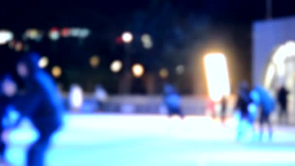 抽象的な背景がぼやけている 冬の夜はオープンエアのアイスリンクでスケートをする人も多いです 新年のクリスマスの休日を祝う カラフルな休日を背景に — ストック動画