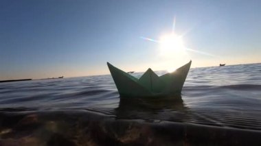 Güneşli yaz günlerinde deniz dalgalarında yüzen küçük yeşil kağıt tekne. Şeffaf su, parlayan güneş, bulutsuz temiz mavi gökyüzü, güneşli yol. Güneşli yol, ışılda. Seyahat hedefi turizmi hayal edin