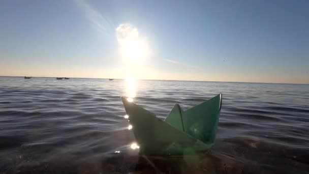 夏の晴れた日のクローズアップで海の波に浮かぶ小さな緑の紙のボート 透明な水 輝く太陽 雲のないきれいな青空 日当たりの良いパス 晴れた道だグレア コンセプト旅行の目標観光夢 — ストック動画