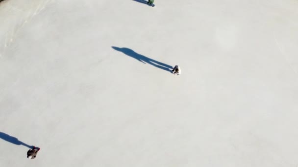 摘要顶部视图 在阳光明媚的冬日 那些在户外溜冰场上投下长长的影子的人在溜冰场上滑冰 公共城市冰场 空中无人驾驶飞机视图 娱乐性体育假日 — 图库视频影像