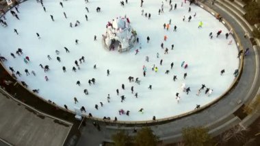 İnsanlar kış akşamı beyaz buz pateni pistinde kayıyorlar. Bir sürü insanla buz pateni pistinde uçmak. Halka açık buz pateni pisti. Üst Manzara. - Hava aracı. Eğlence tatili.