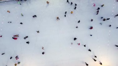 Birçok insan açık havada buz pateni pistinde paten kayıyor. Yılbaşı süsleri, süslemeler, kış gecelerinde parlak çelenkler. Yeni yıl Noel kutlaması. Havadan