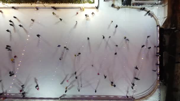 人们在冬夜山顶的室外溜冰场上滑冰 空中无人驾驶飞机视图 灯火通明 投下长长的阴影圣诞假期康乐活动 — 图库视频影像