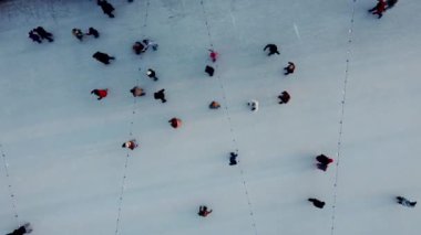 Birçok insan kış güneşi batarken açık hava buz pateni pistinde paten kayıyor. Üst Manzara. Hava aracı görüntüsü. Boş zaman aktivitesi yaşam tarzı spor eğlencesi eglenceli bir arka plan. Renkli arkaplan