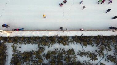 Birçok insan kış güneşi batarken açık hava buz pateni pistinde paten kayıyor. Üst Manzara. Hava aracı görüntüsü. Boş zaman aktivitesi yaşam tarzı spor eğlencesi eglenceli bir arka plan. Renkli arkaplan