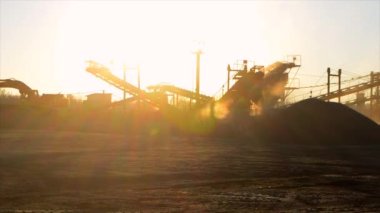 Maden ocağı. Gün batımında granit ocağında ezme tesisi. Crusher taş ocağında. Çok tozlu. Taş kırma. Sanayi tipi çakıl üretimi. Çakıl taşıyıcı. Koni tipi kaya öğütücü, parlayan güneş