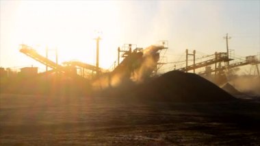 Maden ocağı. Gün batımında granit ocağında ezme tesisi. Crusher taş ocağında. Çok tozlu. Taş kırma. Sanayi tipi çakıl üretimi. Çakıl taşıyıcı. Koni tipi kaya öğütücü, parlayan güneş