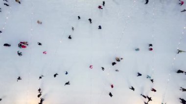Birçok insan açık havada buz pateni pistinde paten kayıyor. Yılbaşı süsleri, süslemeler, kış gecelerinde parlak çelenkler. Yeni yıl Noel kutlaması. Havadan