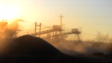 Maden ocağı. Gün batımında granit ocağında ezme tesisi. Crusher taş ocağında. Çok tozlu. Taş kırma. Sanayi tipi çakıl üretimi. Çakıl taşıyıcı. Koni tipi kaya öğütücü, parlayan güneş