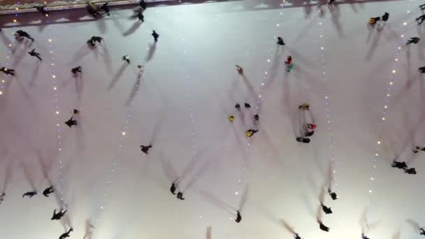 许多人在露天美丽的溜冰场上滑冰 在冬季的夜晚装饰着圣诞的装饰品 装饰品 灿烂的花环 新年佳节庆祝活动 空中业务 — 图库视频影像