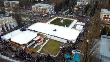 Hava panoramik manzaralı şehir parkı, açık hava buz pateni pisti ve bir sürü insan. Temizlik makinesi buz pistini temizliyor. Halk parkı. Bir sürü insan. Yeni yıl Noel kutlaması tatil geçmişi.