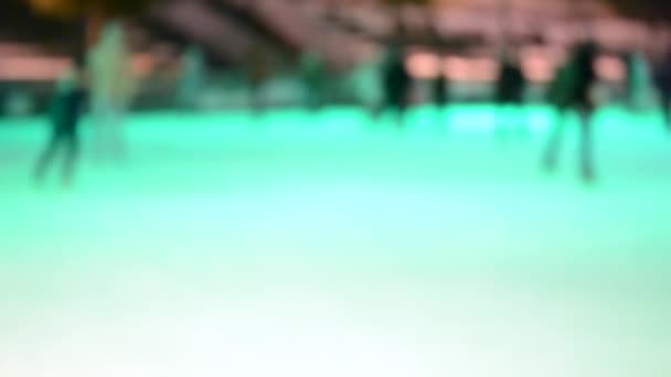 多くの人が冬の夜にオープンエアのアイススケートリンクでスケート 多色音楽着色照明カラフルなバックライト照明輝く活動エンターテイメントぼやけた抽象的な背景 — ストック動画
