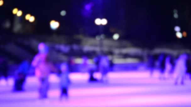 多くの人が冬の夜にオープンエアのアイススケートリンクでスケート 多色音楽着色照明カラフルなバックライト照明輝く活動エンターテイメントぼやけた抽象的な背景 — ストック動画