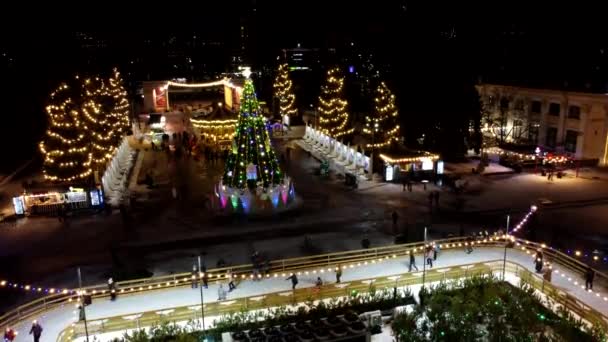圣诞树和人们在露天溜冰场滑冰 在冬季的夜晚装饰着明亮的圣诞装饰品 新年佳节庆祝活动 空中业务 — 图库视频影像
