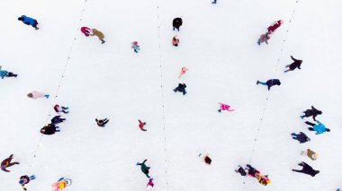 Açık havada buz pateni pistinde kayan insanlar. Üst Manzara. Buz pistinde paten yapan bir sürü insan var. Hava Aracı Görünümü. Güzel Paten Sporu ve Kış Alanı Faaliyetleri