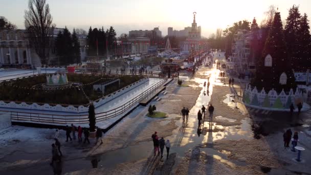 キエフ ウクライナ2022年1月20日 多くの人々は 冬の日没時にクリスマスツリー 異なる建物 フードコート 屋外アイススケートリンクで公園を歩く 空中ドローンビュー アクティビティライフスタイル — ストック動画