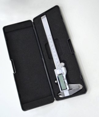 Plastik siyah kutudaki dijital elektronik vernier kalibre beyaz arka planda izole edilmiş. Mühendislik endüstriyel ölçüm ekipmanları. Evrensel yüksek duyarlı ölçüm aygıtı.