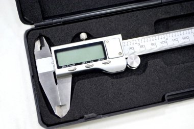 Plastik siyah kutudaki dijital elektronik vernier kalibre beyaz arka planda izole edilmiş. Mühendislik endüstriyel ölçüm ekipmanları. Evrensel yüksek duyarlı ölçüm aygıtı.