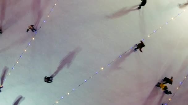 许多人在露天美丽的溜冰场上滑冰 在冬季的夜晚装饰着圣诞的装饰品 装饰品 灿烂的花环 新年佳节庆祝活动 空中业务 — 图库视频影像