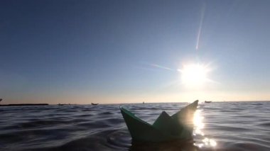 Güneşli yaz günlerinde deniz dalgalarında yüzen küçük yeşil kağıt tekne. Şeffaf su, parlayan güneş, bulutsuz temiz mavi gökyüzü, güneşli yol. Güneşli yol, ışılda. Seyahat hedefi turizmi hayal edin