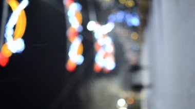 İnsanlar kışın kar yağarken sokakta yürürken süslenmiş Noel ağaçları aydınlatmalarla ve sokak süslemeleriyle yeni yıl arkaplanı bulanıklaştırıyor.
