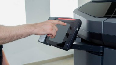 Bir adam dijital ekran monitörüne elinin bir parmağıyla basar. Çoklu Jet Füzyonu. Büyük endüstriyel 3D yazıcı. Endüstriyel ekipman Yeni modern 3D baskı teknolojisi