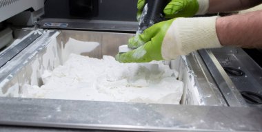 Mane, 3D yazıcının çalışma odasındaki beyaz polyamide tozundan modeller çıkarıyor, toz temizliyor ve kaldırıyor. Toz 3D yazıcıda model oluşturma süreci. Çoklu Jet Füzyon MJF. İşçi elleri