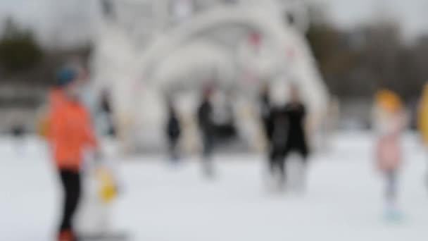 人々は冬の日にアイススケートリンクでスケートをします 背景がぼやけている レジャーエンターテイメント休暇週末休暇冬の活動ライフスタイル 冬の楽しみの公共都市の創造を楽しむ — ストック動画