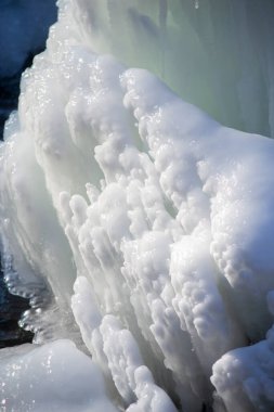 Güneşli bir kış gününde parkta buzlu çeşme. Donmuş suyla çeşme. Soğukta buzlu bir çeşmeden gelen bir su jeti. Gündüzleri arka plan buz ve karla kaplıydı.