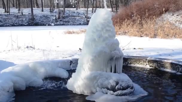 在冬日阳光明媚的日子 公园里的冷泉 有冰水的泉源 一股从在寒冷中结冰的喷泉喷出的水 公园里白天被冰雪覆盖的背景 — 图库视频影像