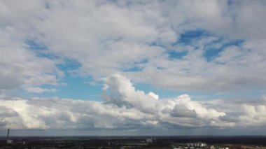 Fast movement of white cumulus clouds in blue sky during strong wind during day. Timelapse. Aerial drone view. Panoramic natural background. Rain. Rainy cloudy weather. Cloudscape. Scenic landscape.
