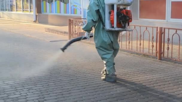 Man Airtight Suit Sprays Disinfecting Liquid Pavement Street City Backdrop — Stockvideo