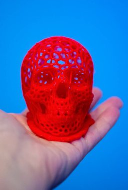 A man holding on his hand a model of a prototype of a human skull printed on a 3D printer