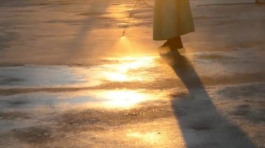 Man in airtight suit sprays disinfecting liquid a pavement on a street in the city against the backdrop of a sunset. Sanitation workers clean a crosswalk. Sanitary measures. coronavirus pandemic