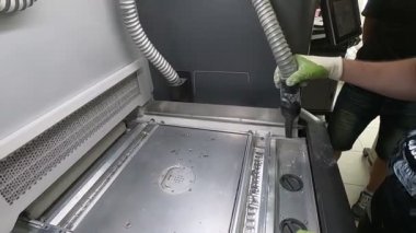 Bir erkek işçi, elektrikli süpürgeyle endüstriyel 3D yazıcının yüzeyini beyaz tozdan temizliyor. Çoklu Jet Füzyon MJF 3D baskı. Çalışma süreci