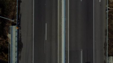 Cars driving along highway on autumn sunny day. Automobile road with white markings between agricultural fields. View of cars driving on paved road. Automobile vehicles. top view. Aerial drone view.