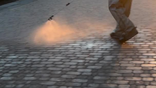 Man Airtight Suit Sprays Disinfecting Liquid Pavement Street City Backdrop — Vídeo de stock