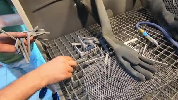 男性労働者は ショットブラスト機内のショットブラスト機でそれらを洗浄した後 3Dプリントされた金属モデルを拾います 中で撃たれた — ストック動画