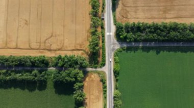 Otomobil asfalt yolu, tarımsal tarlalar arasında giden arabalarla olgunlaşmış sarı buğday ve farklı yeşil tarım ürünleri. Hava aracı görüntüsü. Tarım tarımsal ekin arazisi