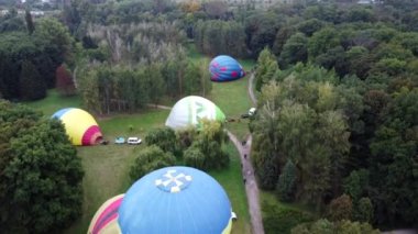 Bila Tserkva, Ukraine, August 3, 2021: Balloon Festival. Inflating big balloon aerostat. Several balloons lie on ground and inflate in forest. Raising balloons to sky. Entertainment rest