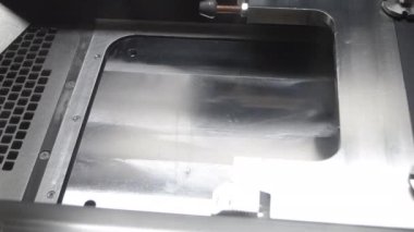 Alignment of metal powder on working surface of 3D printer for metal before starting work. Gray material metal powder for printing objects by 3d printer for metal. Working 3d printer inside.