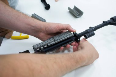 3D baskılı silah parçaları. İnsan tüfeği monte eder, bazı parçalar 3 boyutlu yazıcıya basılır. Silahın gri renginin ayrıntıları poliyamid tozundan 3D yazıcıya basılmış. İlerici katkı teknolojisi