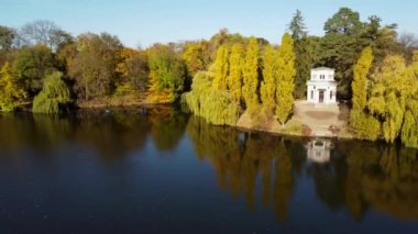 Beautiful autumn landscape. Lake,smooth mirror water surface, white boat, trees yellow leaves, architecture, blue sky, park on autumn sunny day. Natural scenery. Nature background. Environment. Aerial