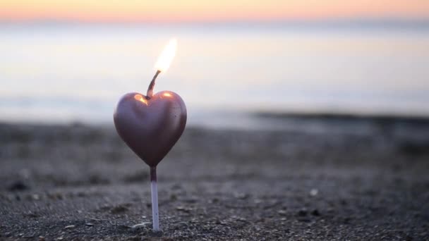 日落时分 海边的沙滩上燃着心形的蜡烛 在太阳升起的背景下 在沙中燃烧着心形的蜡烛 浪漫的浪漫心情 圣瓦伦丁日 — 图库视频影像