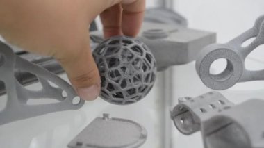 Person putting model printed on 3D printer to other models printed on 3D printer close-up. Three-dimensional object gray color printed on 3D printer. Technology MJF. Modern new innovation technology