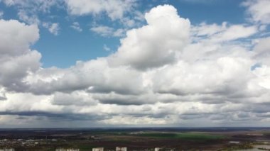 Fast movement of white cumulus clouds in blue sky, strong wind on day. Aerial drone view. Natural panoramic background. Rain. Cloudscape. Scenic landscape. Timelapse. Rainy cloudy weather.
