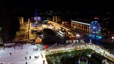 Kyiv, Ukrayna 20 Ocak 2022: İnsanlar açık havada buz pateni pistinde yeni yıl süslemeleri, aydınlatmalar, kış gecelerinde parlak çelenkler ile kayıyorlar. Yılbaşı Noel tatili